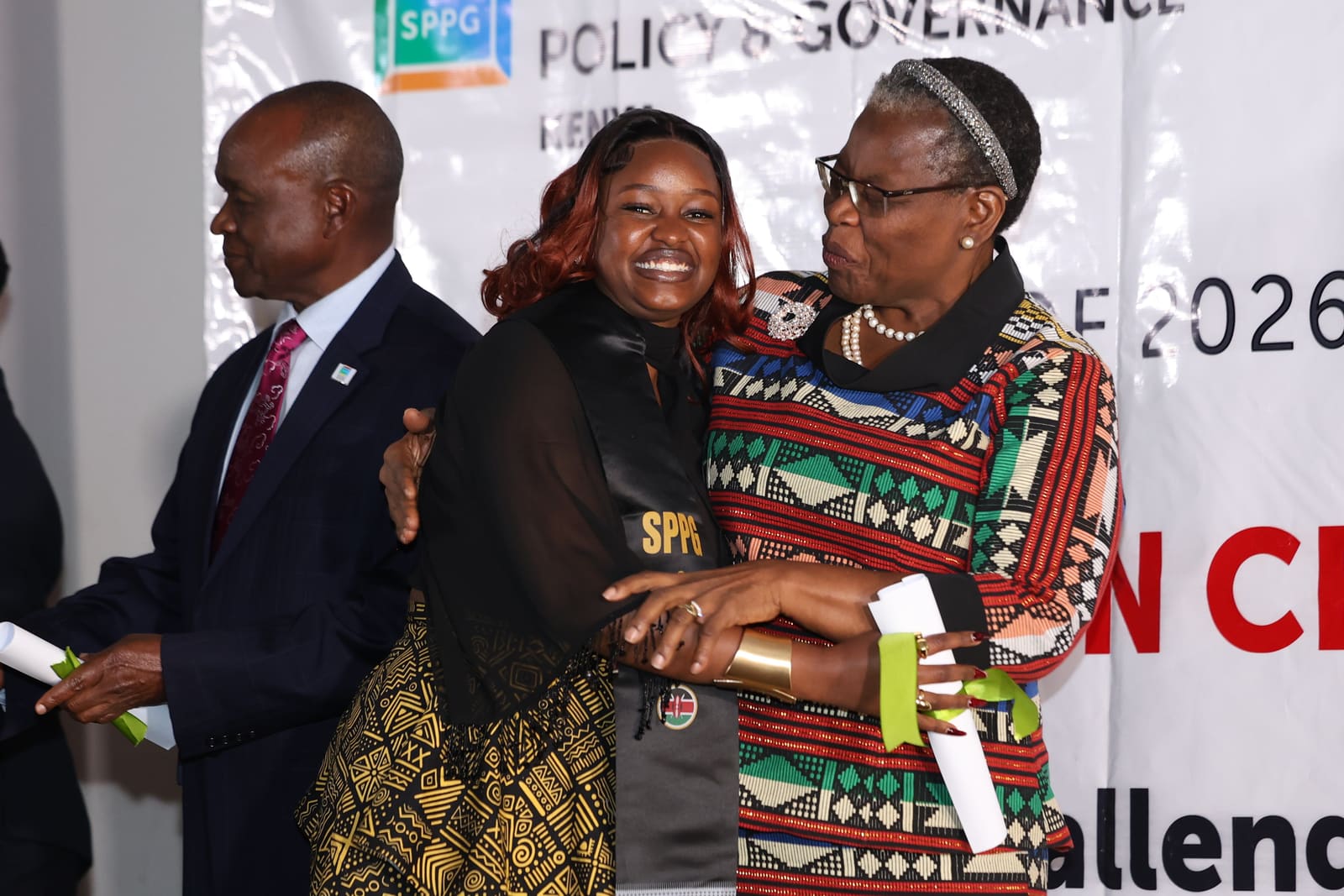 A Kenyan graduate embraced after receiving her certificate